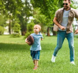 Young child playing football with parent